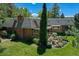 Expansive backyard featuring lush landscaping, a brick chimney, and a covered patio at 12135 W Applewood Knolls Dr, Lakewood, CO 80215