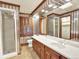 Stylish bathroom with a glass-enclosed shower, long vanity, and decorative wallpaper at 12135 W Applewood Knolls Dr, Lakewood, CO 80215