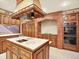 A kitchen with a large center island, brick details, custom hood, and stainless appliances at 12135 W Applewood Knolls Dr, Lakewood, CO 80215