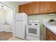 Functional kitchen with white appliances, wooden cabinets and a peek into the entry hall at 1755 Quince St, Denver, CO 80220