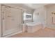 Bright bathroom featuring a glass-enclosed shower and a large soaking tub with tile surround at 3915 Miller St, Wheat Ridge, CO 80033