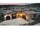 An elegant stucco and stone home on a hillside, featuring a tiled roof, and mature landscaping, adding curb appeal at 8310 Raphael Ln, Littleton, CO 80125