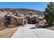 Elegant stucco home with tile roof, stone accents, and a long, winding driveway, set against rolling hills at 8310 Raphael Ln, Littleton, CO 80125