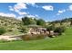 Scenic backyard pond with waterfall feature, creating a relaxing and beautiful natural setting next to green grass and rolling hills at 8310 Raphael Ln, Littleton, CO 80125