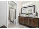 Neat bathroom with dark wood cabinet, granite counters, mirror, and bath with shower at 1882 W 67Th Ave, Denver, CO 80221