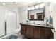 Bathroom featuring dark wood vanity, large mirror, updated shower, and gray tile at 1882 W 67Th Ave, Denver, CO 80221