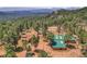 Aerial view featuring a house and barn nestled amongst pine trees and rolling hills at 26526 Gray Buck Trl, Conifer, CO 80433