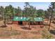 This aerial view showcases an outbuilding with a horse stable, surrounded by trees at 26526 Gray Buck Trl, Conifer, CO 80433