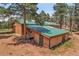 This outbuilding is a tan color with a green roof, with an entrance on the side at 26526 Gray Buck Trl, Conifer, CO 80433