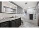 Bathroom featuring a stylish vanity, a large mirror, and a shower-tub combo with tiled walls at 703 S Oneida Way, Denver, CO 80224