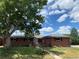 Charming red brick home with a well-maintained lawn, mature trees, and a welcoming walkway at 703 S Oneida Way, Denver, CO 80224