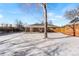 Backyard view showing covered patio, brick home, and snow-covered yard at 914 Quari Ct, Aurora, CO 80011