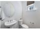 Modern half-bath with a white vanity, round mirror, and natural light at 12336 W 52Nd Ave, Wheat Ridge, CO 80033