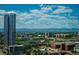 Expansive city view with a modern high-rise building and snow-capped mountains in the distance under a bright, cloudy sky at 1700 Bassett St # 1808, Denver, CO 80202