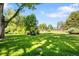 Green lawn with a flower garden, mature trees, and a stone walkway at 4181 S Colorado Blvd, Cherry Hills Village, CO 80113