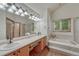 Bright main bathroom with dual sinks, soaking tub, large mirror, and wood-look flooring at 19149 E Ida Dr, Aurora, CO 80015
