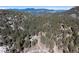 Aerial view of a mountain home surrounded by green pine trees and mountain views at 24949 N Mountain Park Dr, Evergreen, CO 80439