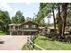 A charming green two-story home features an attached garage and multiple balconies, surrounded by lush trees at 24949 N Mountain Park Dr, Evergreen, CO 80439