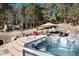 This backyard features a hot tub, stone patio and a lovely seating area with a fire pit at 24949 N Mountain Park Dr, Evergreen, CO 80439