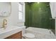 Stylish bathroom features a bathtub with green tile, a modern sink, and gold hardware at 4551 Julian St, Denver, CO 80211