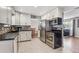 Modern kitchen with stainless steel appliances, white cabinetry, tile backsplash and flooring at 9430 Perry St, Westminster, CO 80031