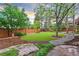 Serene backyard featuring a lush lawn, mature trees, and a winding stone pathway at 16416 E Powers Pl, Centennial, CO 80015