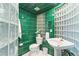 Unique green tiled bathroom featuring decorative glass block accents, toilet and pedestal sink at 16416 E Powers Pl, Centennial, CO 80015