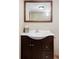 Bathroom vanity featuring dark wood cabinet, white sink, chrome faucet, and wood-framed mirror at 9000 W 4Th Pl, Lakewood, CO 80226
