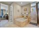 Relaxing bathroom boasts tub with travertine surround and shower with frameless glass door at 7947 Monarch Rd, Larkspur, CO 80118