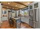 Bright kitchen with wood beams, stainless steel appliances, a center island, and a farmhouse sink at 7947 Monarch Rd, Larkspur, CO 80118