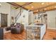 Open-concept living room with rustic wood beams, stairs, and a modern island with bar seating at 7947 Monarch Rd, Larkspur, CO 80118