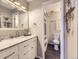 A well-lit bathroom featuring marble countertops, white cabinets, a modern sink, and a shower with tiled walls at 17404 E Prentice Cir, Centennial, CO 80015