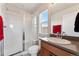 This bathroom includes a glass shower with a bench, a window, and a light-colored vanity at 10968 Lewiston St, Commerce City, CO 80022