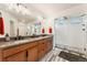 Primary bathroom featuring double vanity, walk in shower, and wooden cabinets at 10968 Lewiston St, Commerce City, CO 80022