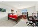 This bedroom features a bed with a red comforter and a window that faces a neighborhood home at 10968 Lewiston St, Commerce City, CO 80022