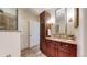 Well-lit bathroom with a custom vanity, decorative mirror, and tiled floors next to glass shower at 7600 Landmark Way # 613-2, Greenwood Village, CO 80111