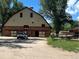 Rustic barn with brick and white trim surrounded by trees and green space at 7369 S Gore Range Rd # 208, Littleton, CO 80127