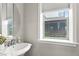 Cozy bathroom features a round mirror, pedestal sink, and natural light at 5925 Hanover St, Denver, CO 80238