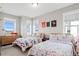 Comfortable bedroom with two twin beds, three large windows, light grey walls, and unique colorful bedspreads at 5925 Hanover St, Denver, CO 80238