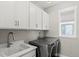 Functional laundry room featuring a sink, sleek washer and dryer, upper cabinets, and a window at 5925 Hanover St, Denver, CO 80238