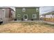 Exterior view of a green home with a spacious yard featuring gravel, and a patio, complemented by a grill at 676 Hearthstone Ave, Brighton, CO 80601