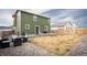 A spacious backyard area featuring a green home exterior, gravel landscaping, and an outdoor seating area at 676 Hearthstone Ave, Brighton, CO 80601