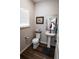 Cozy bathroom with a pedestal sink, toilet, and wood-style flooring at 676 Hearthstone Ave, Brighton, CO 80601