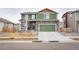 Charming two-story home features a green exterior, stone accents, and a matching green two-car garage at 676 Hearthstone Ave, Brighton, CO 80601