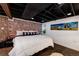 Exposed brick wall accents the primary bedroom with black ceiling, recessed lighting, and white plush comforter at 1172 Harrison St, Denver, CO 80206