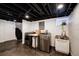 Finished basement laundry room with black ceiling, white walls, stainless steel appliances, and utility sink at 1172 Harrison St, Denver, CO 80206