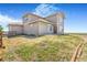 Rear exterior view of a two-story home with light siding, lawn, and access to open land at 497 Valley Way, Bennett, CO 80102