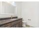 Bathroom vanity with a dark countertop, a modern sink and fixtures, and white cabinets at 497 Valley Way, Bennett, CO 80102