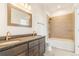 Bathroom featuring double sinks with a dark vanity, a bathtub, and tiled walls in the shower at 497 Valley Way, Bennett, CO 80102