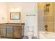 Bathroom features double sinks with granite countertop, dark vanity, tiled tub/shower, and overhead lights at 497 Valley Way, Bennett, CO 80102